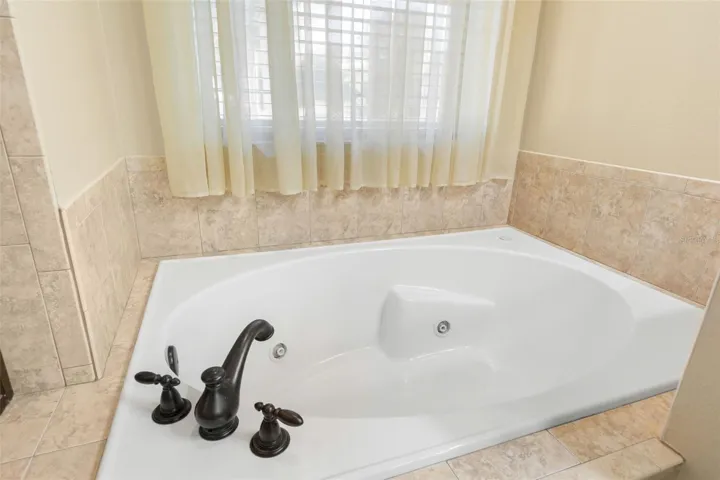 Unwind in the generously sized soaking tub, positioned beneath a window that brings soft natural light into the space.