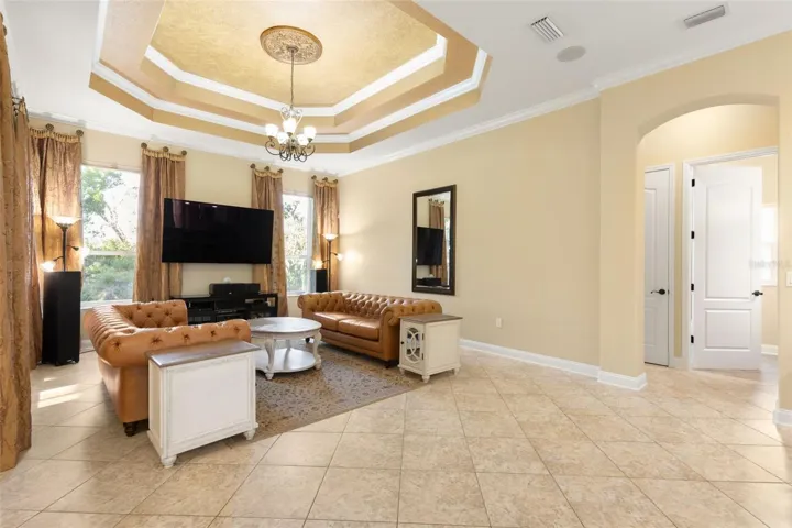 An elegant gathering room where a dramatic tray ceiling, crown molding and decorative lighting create a beautiful setting for relaxing and entertaining.
