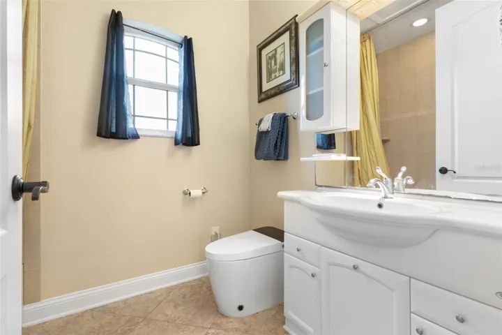 A private full bathroom complements the upstairs suite, featuring a vanity with storage, natural light and a tub/shower combination.