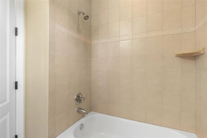 Decorative tile accents and a built-in corner shelf add thoughtful details to the upstairs bathroom's tub/shower combination.