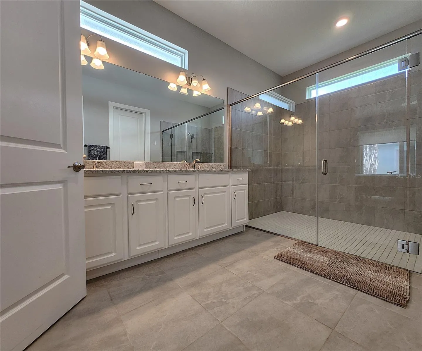 Master bathroom includes large walk-in  tiled shower, water closet, walk-in closet, dual sink vanity, granite countertops