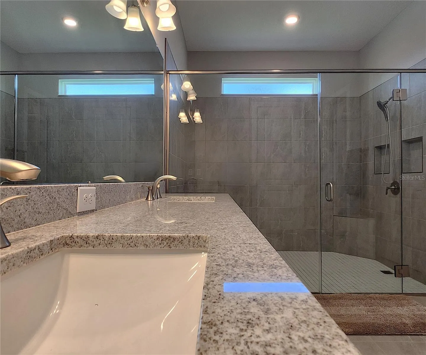 Master bathroom includes large walk-in  tiled shower, water closet, walk-in closet, dual sink vanity, granite countertops