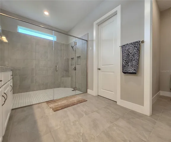 Master bathroom includes large walk-in  tiled shower, water closet, walk-in closet, dual sink vanity, granite countertops
