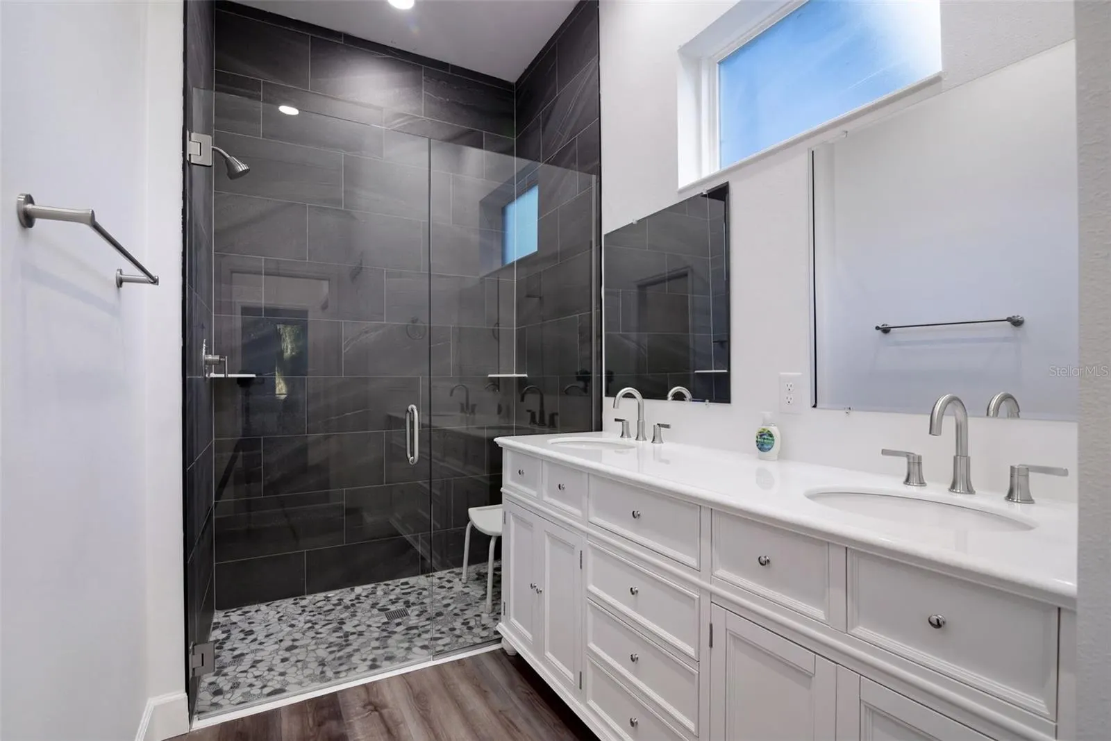 Primary bath: dual sinks, glass walk-in shower, and private water closet