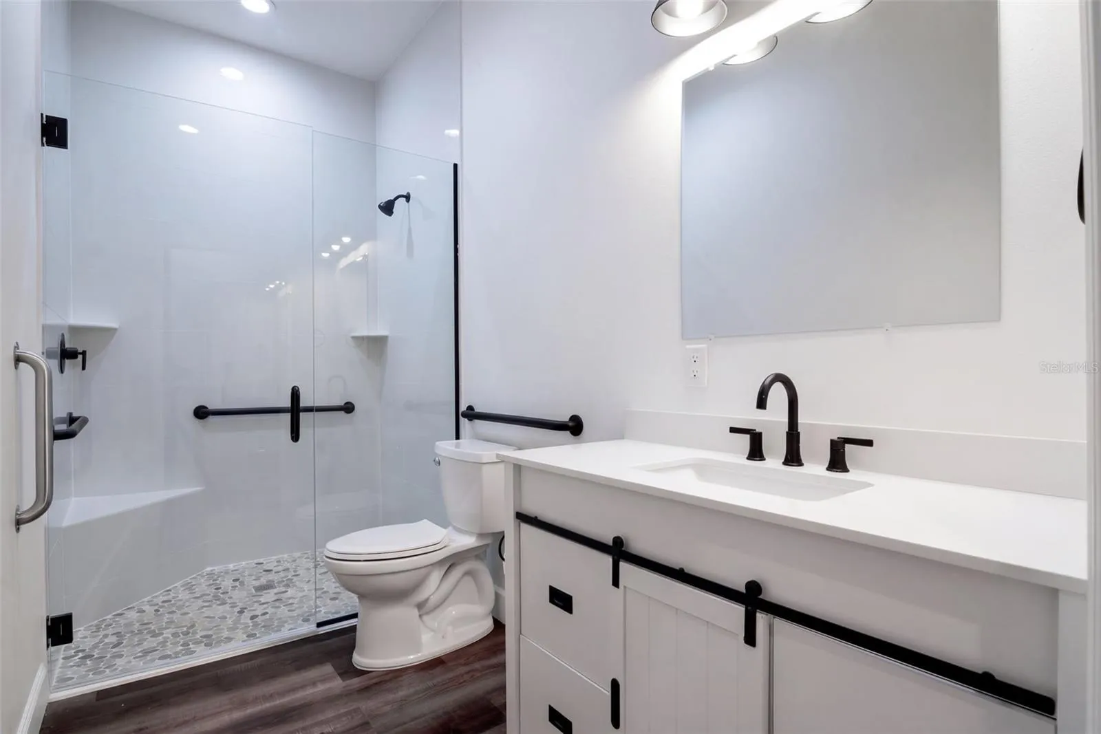 Guest bath with glass walk-in shower, grab bars, and matte black fixtures