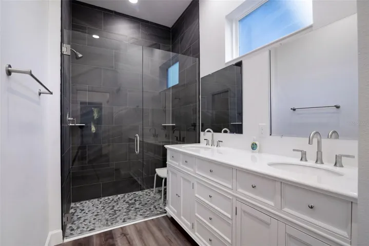 Primary bath: dual sinks, glass walk-in shower, and private water closet