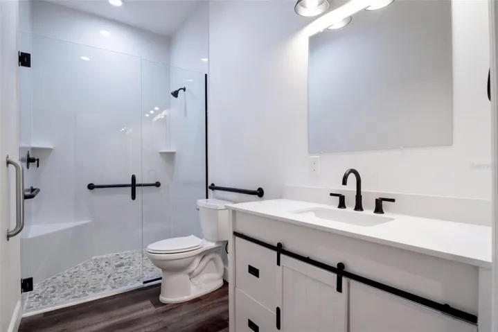 Guest bath with glass walk-in shower, grab bars, and matte black fixtures