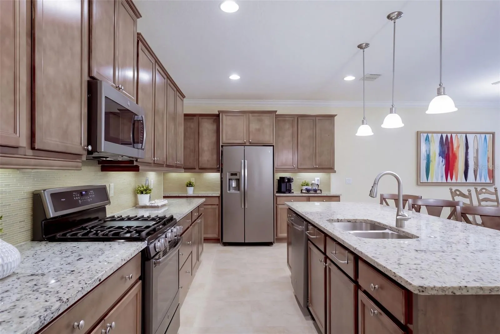 Kitchen w/ a 5-burner natural gas convention range, stainless steel appliances &amp; pendant lighting above breakfast island