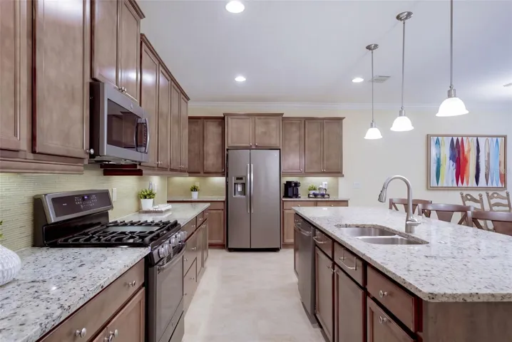 Kitchen w/ a 5-burner natural gas convention range, stainless steel appliances &amp; pendant lighting above breakfast island