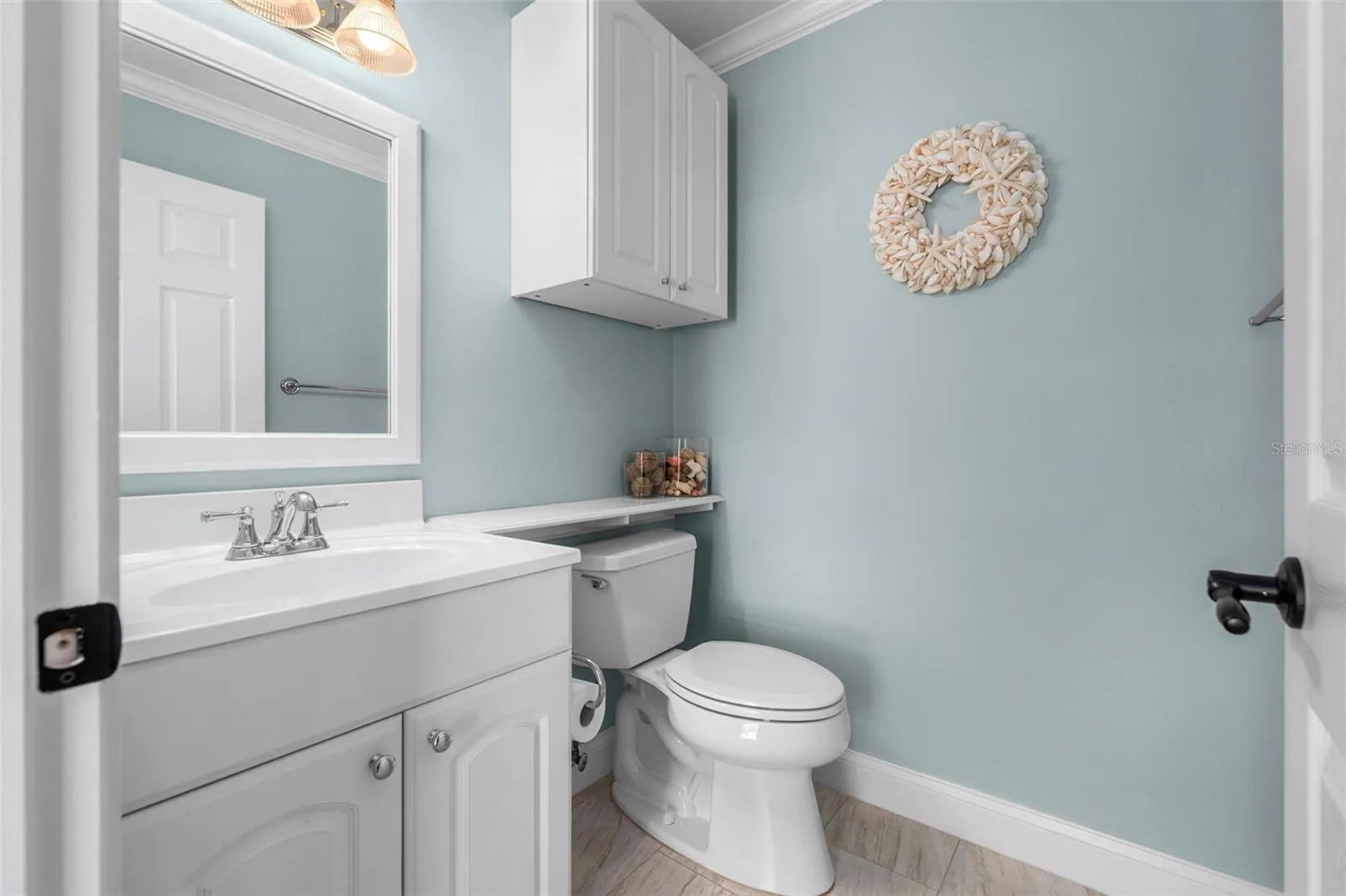 White cabinetry, crown molding, and soothing blue walls give this convenient half bath a polished finish.