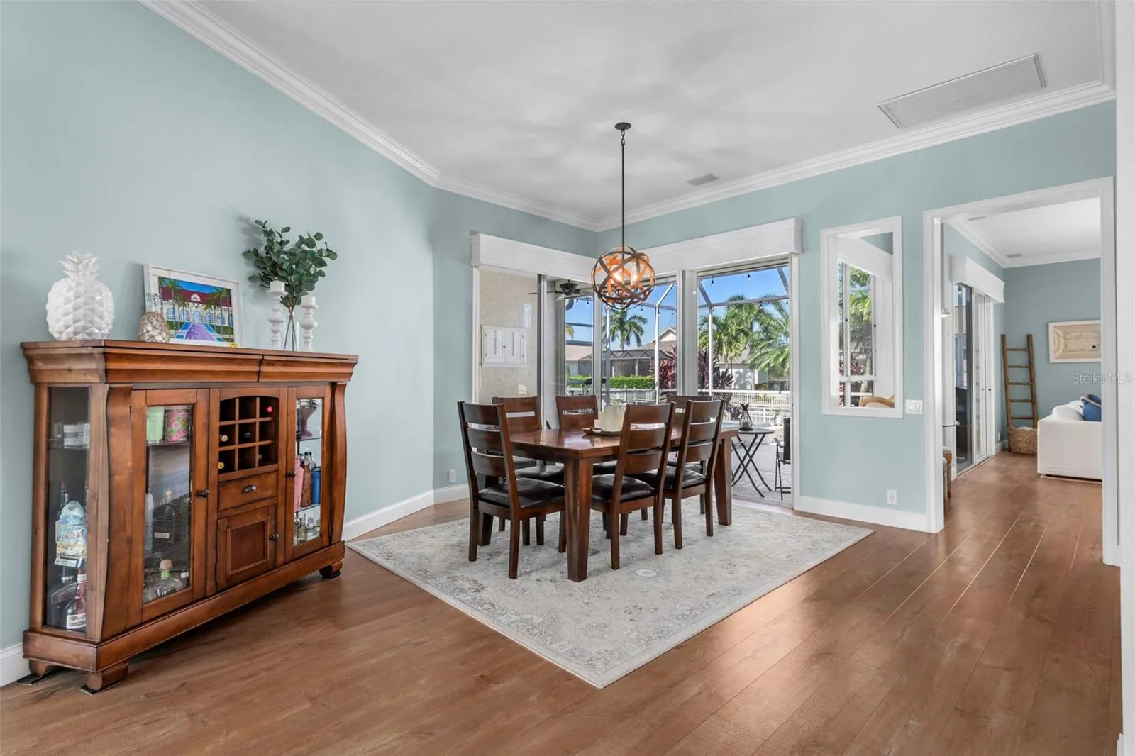 An airy dining space with crown molding, warm flooring, and an easy connection to outdoor entertaining.