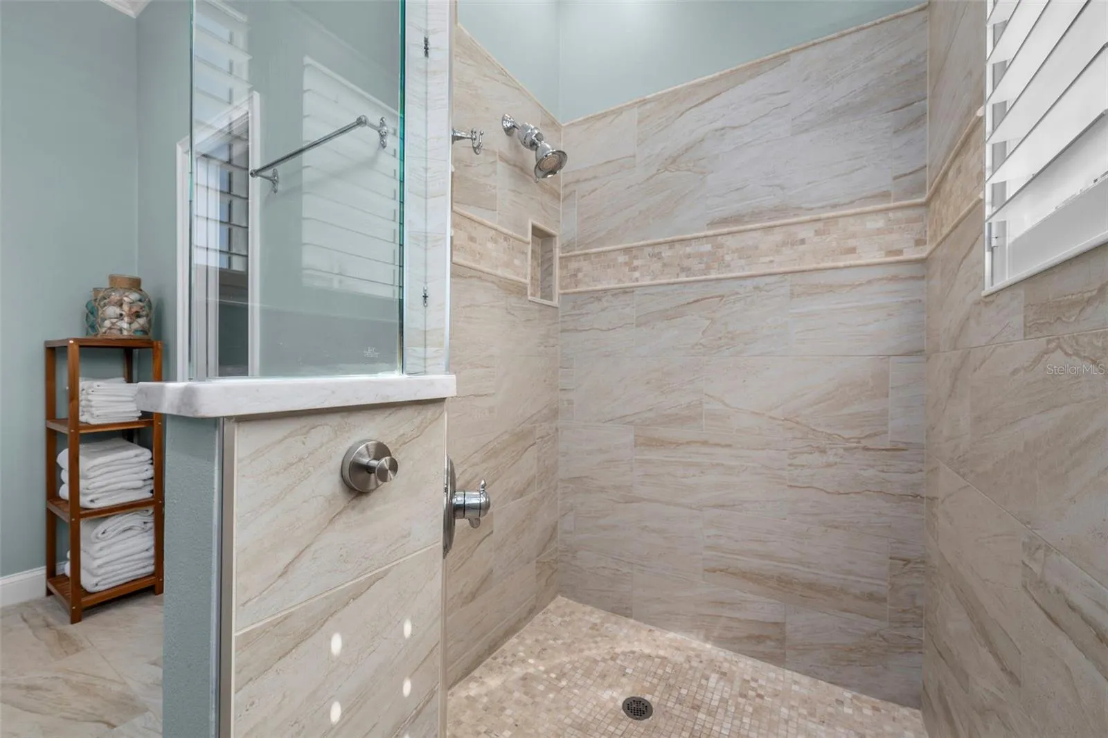 A spacious walk-in shower pairs warm tile tones with glass accents for a relaxing, spa-inspired feel.