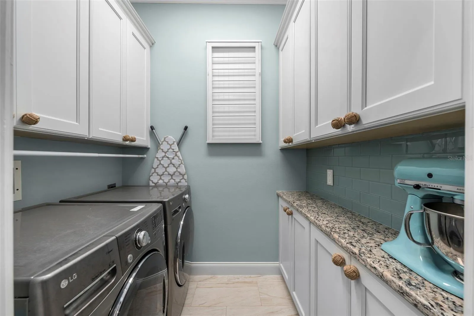 Generous cabinetry, granite counter space, and a coordinating tile backsplash make laundry day a little more enjoyable.