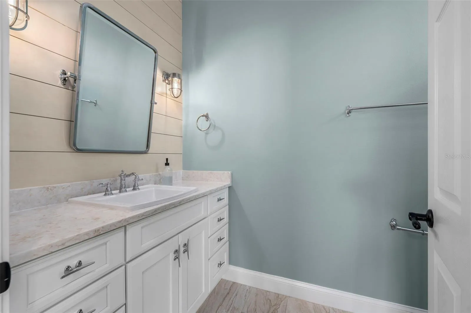 Shiplap accents, nautical-inspired lighting, and a generous vanity bring coastal charm to the renovated guest bath.
