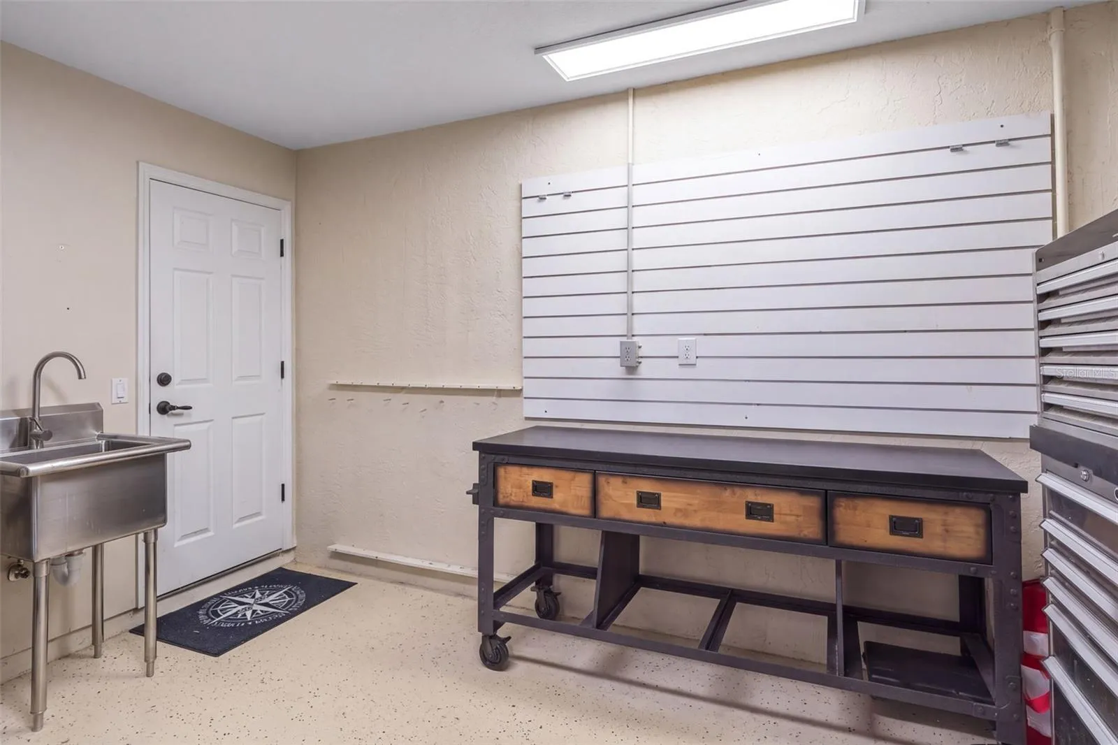 A dedicated garage work area with a utility sink and wall-mounted storage provides a practical spot for projects and organizing gear.