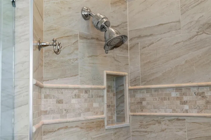 Decorative tilework, polished fixtures, and a recessed niche give the shower a beautifully finished look.