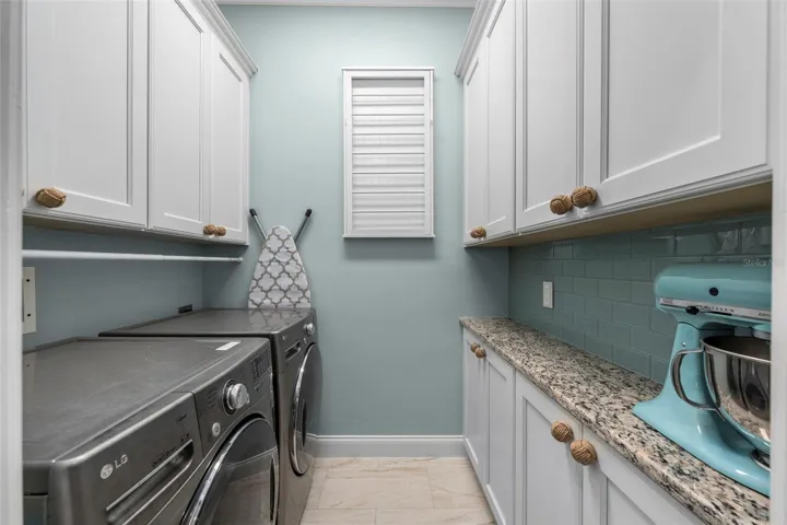 Generous cabinetry, granite counter space, and a coordinating tile backsplash make laundry day a little more enjoyable.