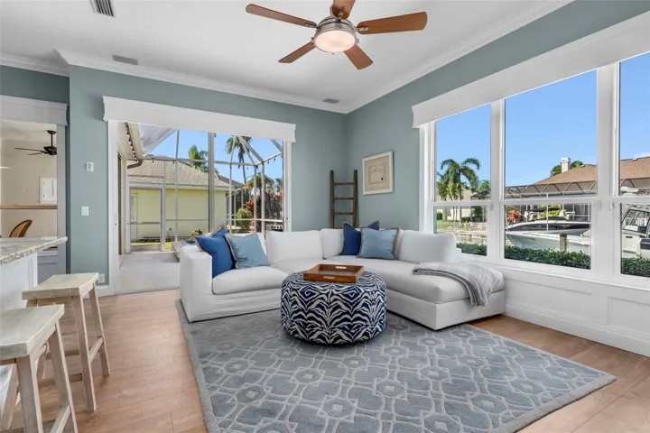 Generous windows frame the waterfront setting, while crown molding and warm flooring give the room a finished feel.