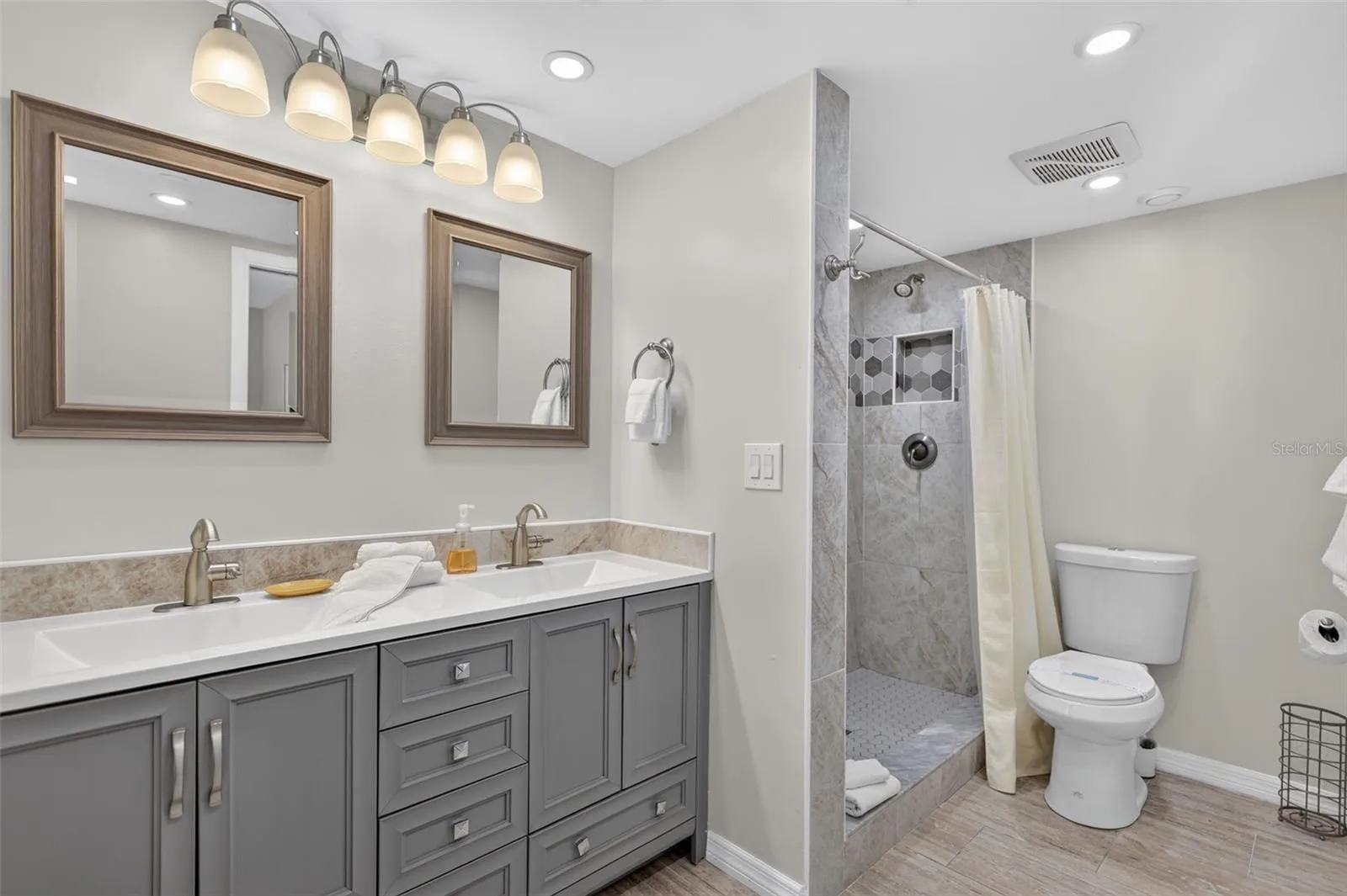 Primary bathroom featuring a modern dual-sink vanity and a spacious walk-in tiled shower.