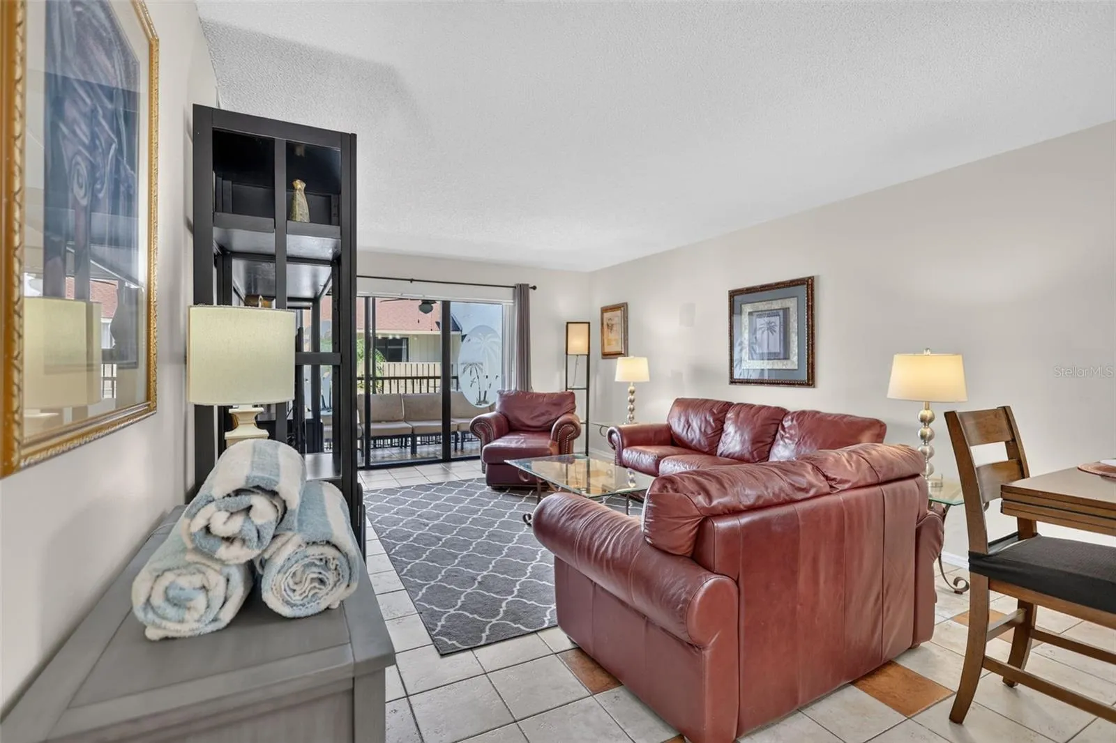Spacious living room featuring sliding glass doors that open to a balcony overlooking the pool.