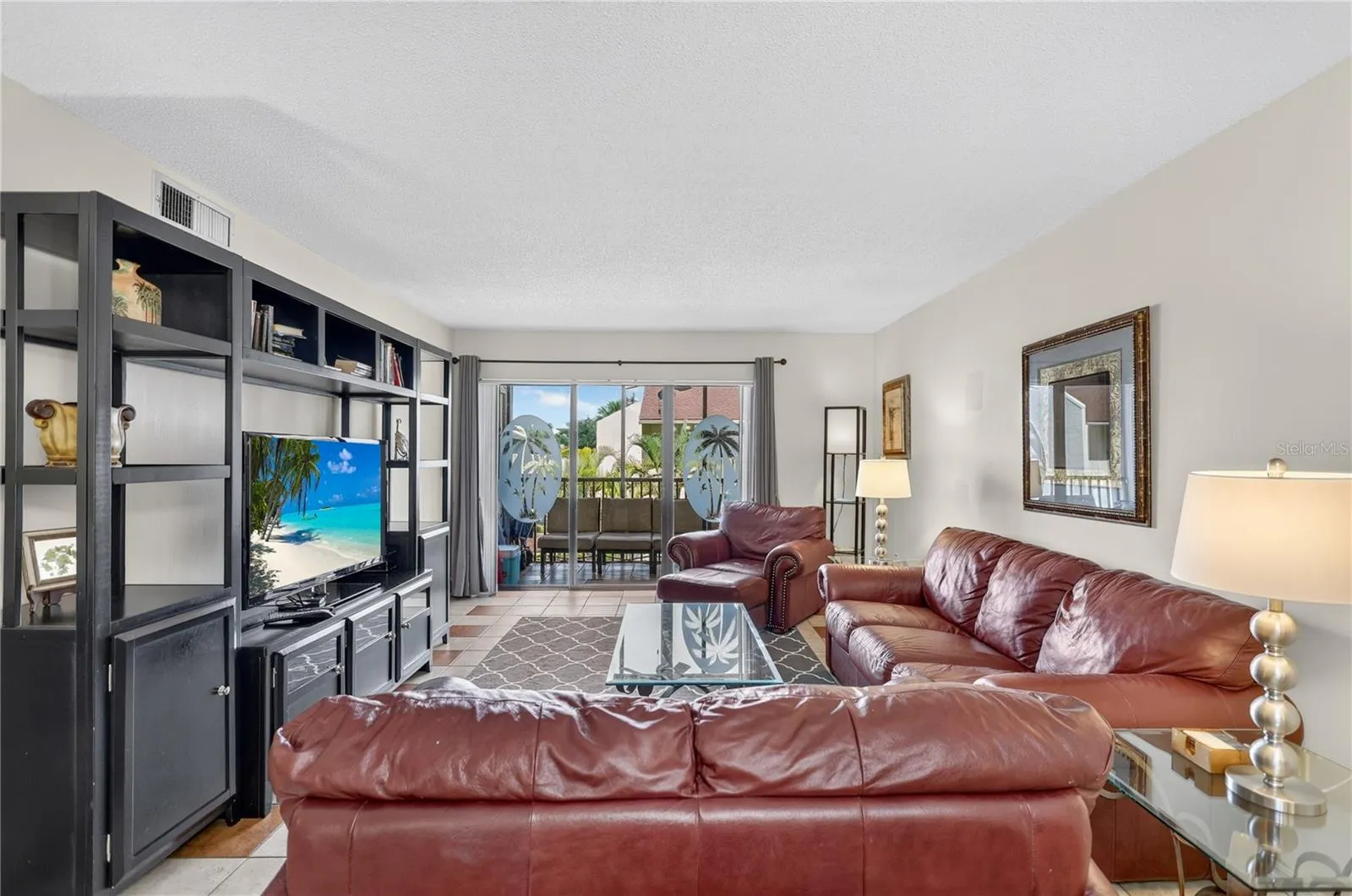 Spacious living room featuring sliding glass doors that open to a balcony overlooking the pool.