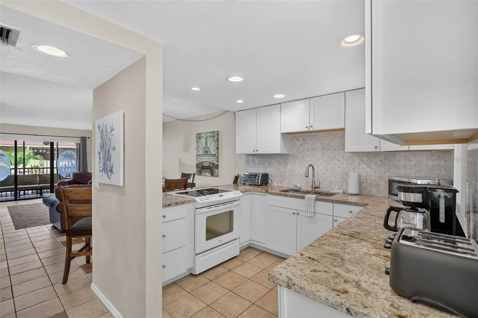 Spacious kitchen featuring granite countertops, a custom tile backsplash, and sleek modern cabinetry.
