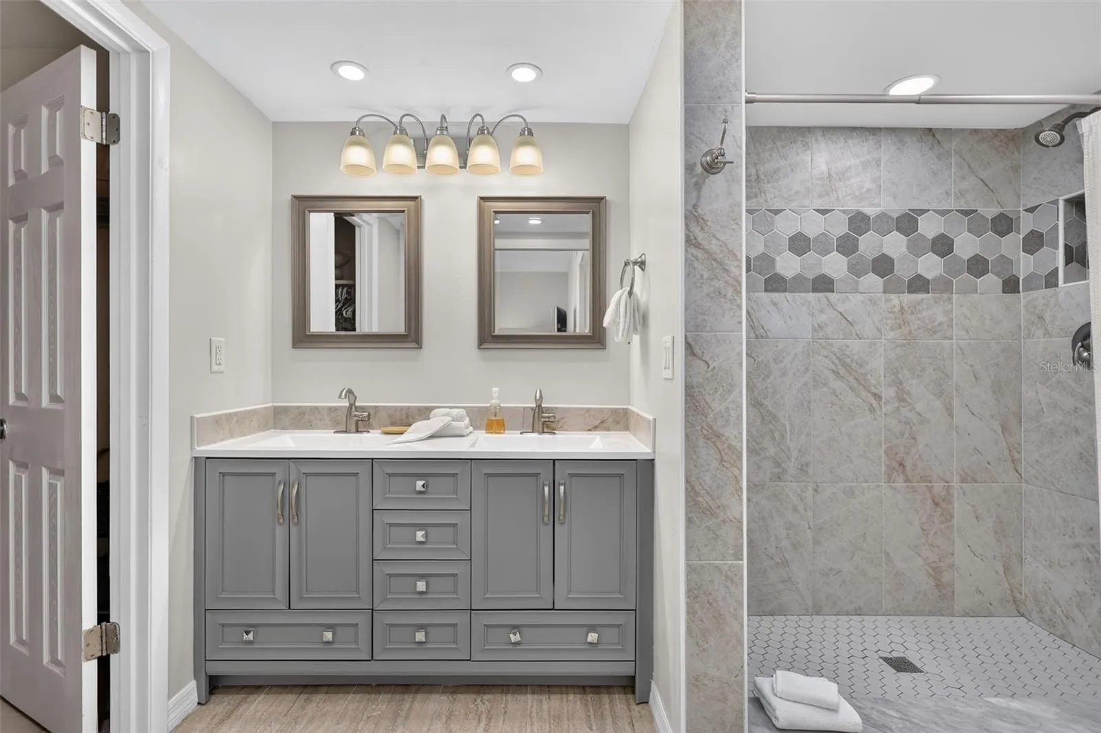 The primary bathroom features beautifully tiled walkin shower, dual sinks, dual mirrors, and generous lighting.