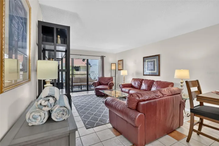 Spacious living room featuring sliding glass doors that open to a balcony overlooking the pool.