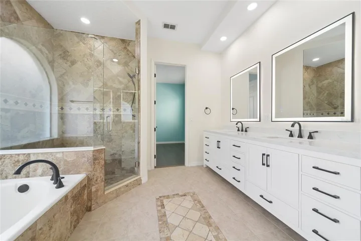 Enjoy this bright and beautifully updated private primary bathroom with garden tub, separate shower, and double vanity with dual sinks.