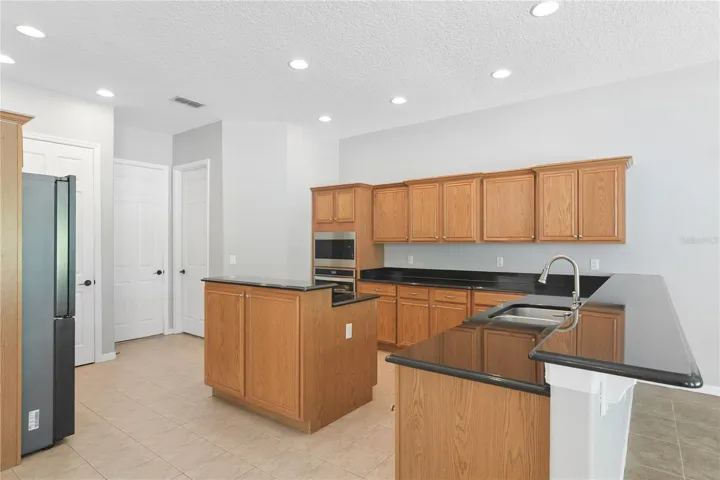 Continuing thru to the kitchen that has updated appliances including an ice maker and wine fridge. This is also open concept to a breakfast nook/dinette and the family room.