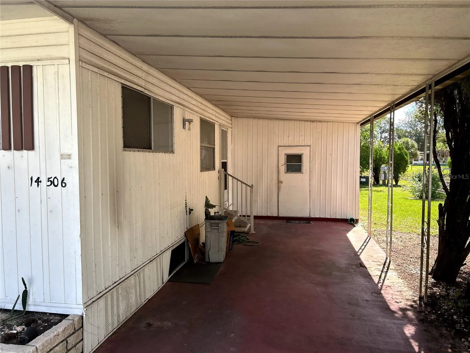 covered carport, utility room/ laundry room and entrance to kitchen.