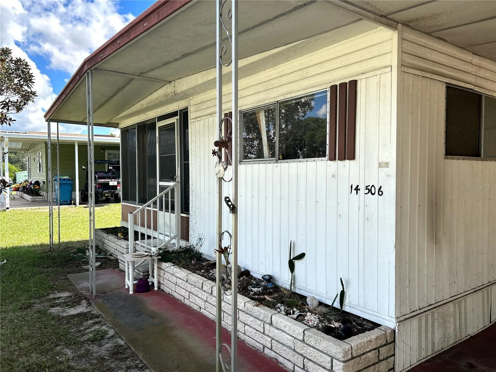 Front view of sidewalk and covered porch area to covered carport.