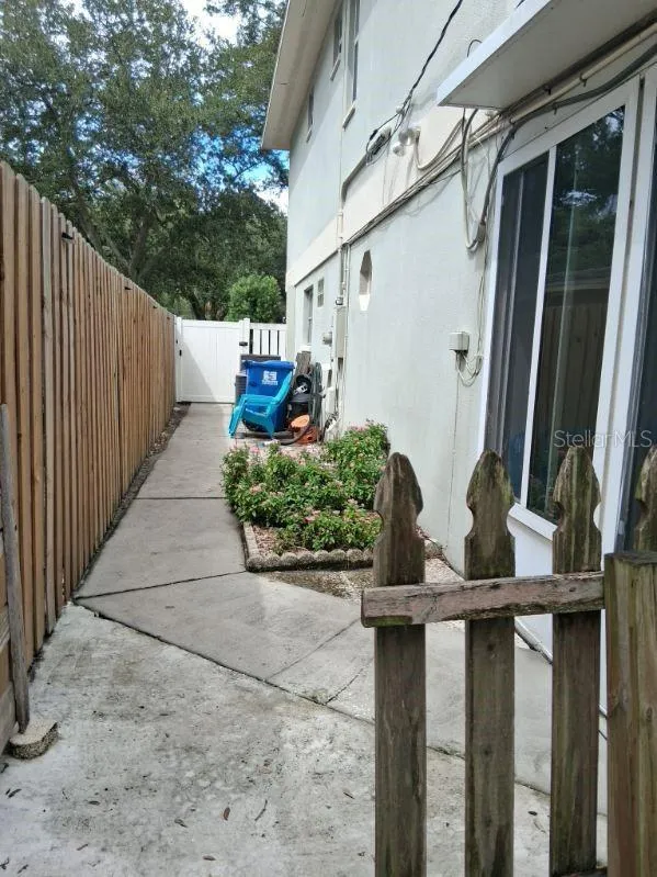 South side of home with vinyl gate to driveway, and man door into garage