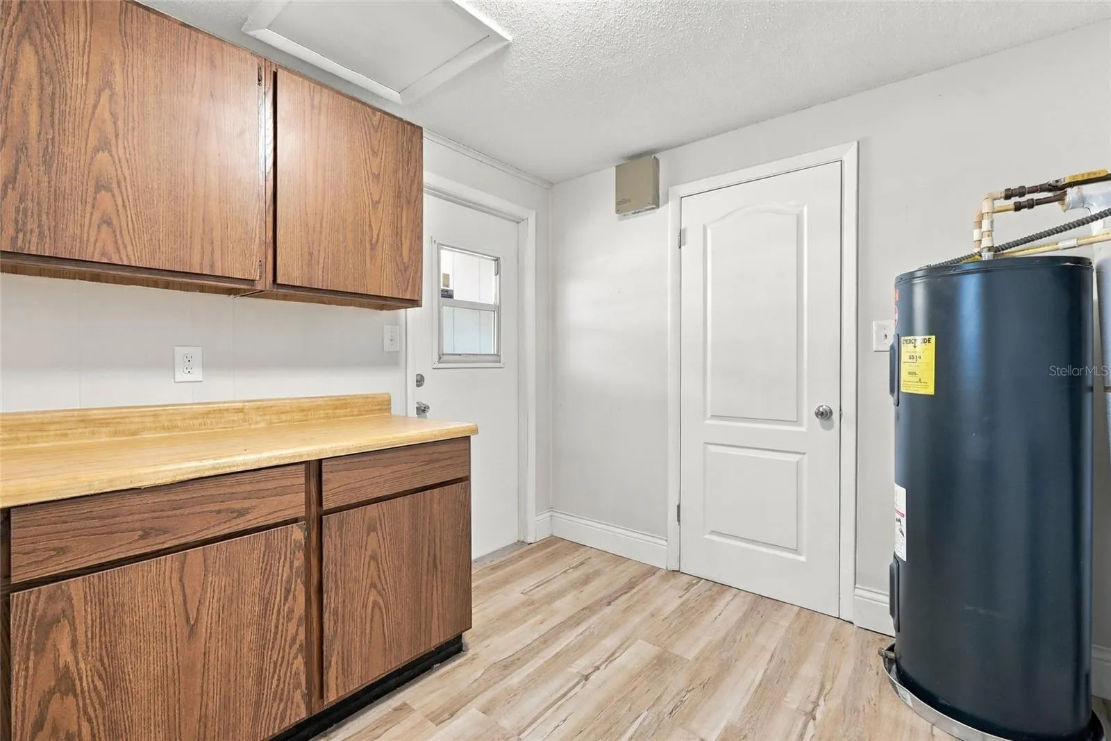 Inside utility with cabinets with left door to carport and other to dining area.