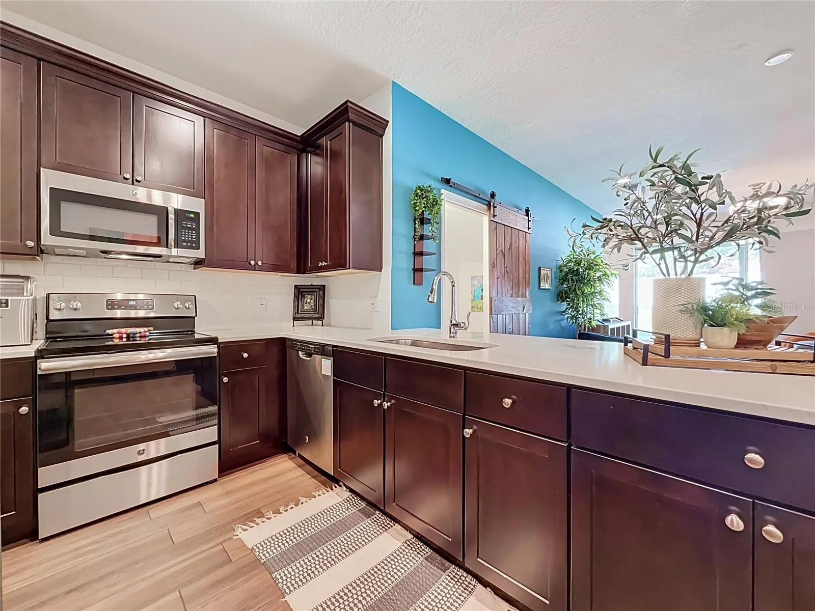 The well-appointed kitchen offers SOLID WOOD CABINETRY, GRANITE countertops, stainless steel appliances, a breakfast bar, and ample storage.