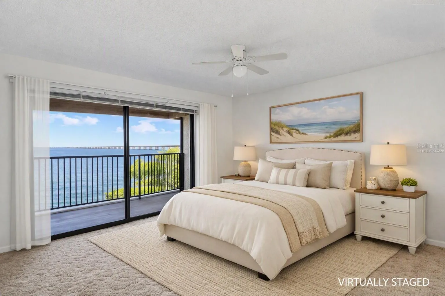 Virtually staged - primary bedroom over looking the balcony with full panoramic water views