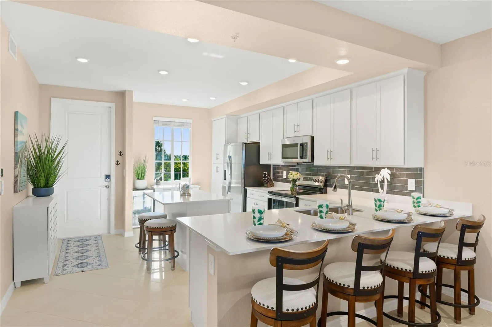 Open floor plan featuring a spacious kitchen with abundant counter space for meal preparation and ample seating, ideal for cooking and entertaining, all overlooking the living area with beautiful golf course, water, and preserve views.