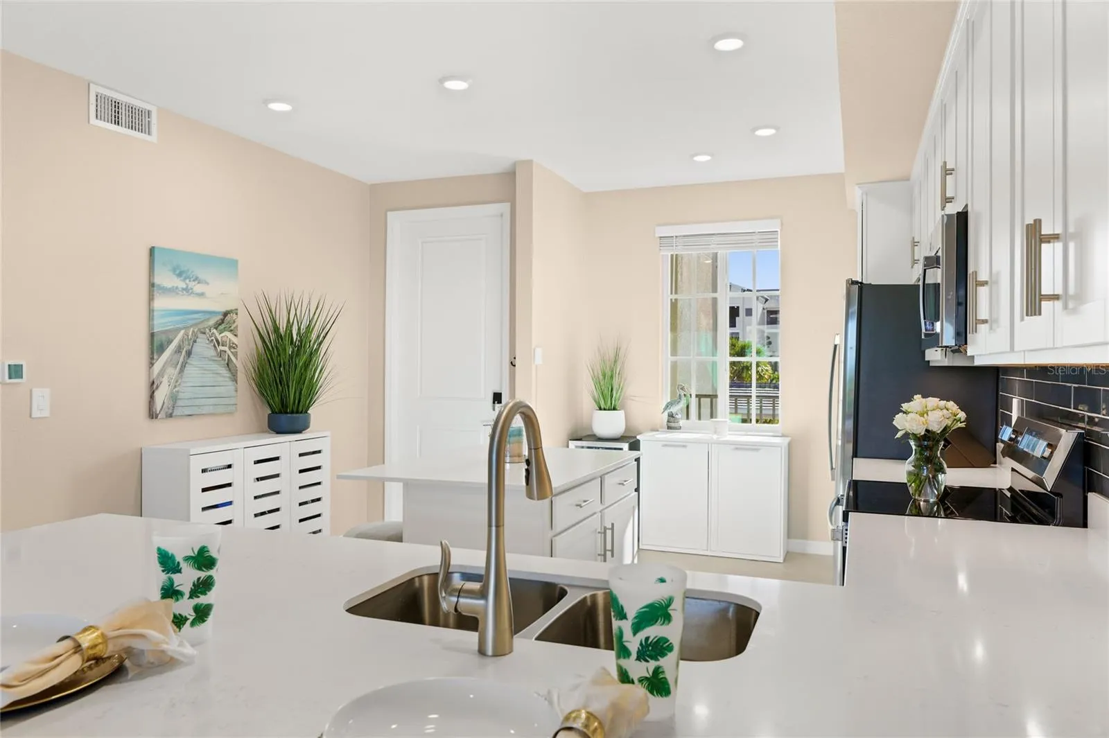 Open floor plan featuring a spacious kitchen with abundant counter space for meal preparation and ample seating, ideal for cooking and entertaining, all overlooking the living area with beautiful golf course, water, and preserve views.