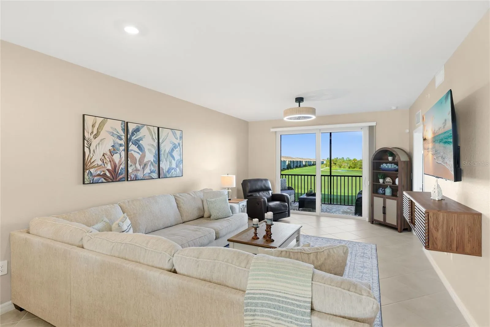 Living Room overlooking the spacious Lanai with beautiful golf course, water, and preserve views.