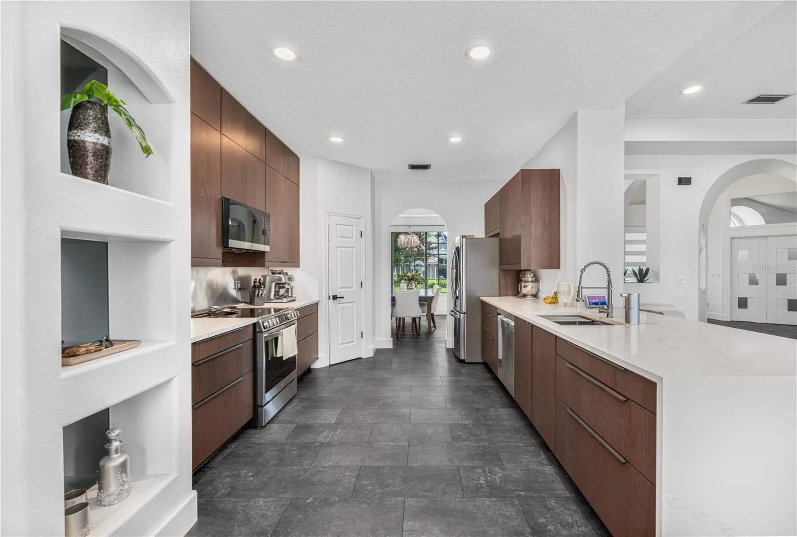 Modern kitchen featuring beautiful cabinetry, waterfall quartz counters, and stainless steel appliances.