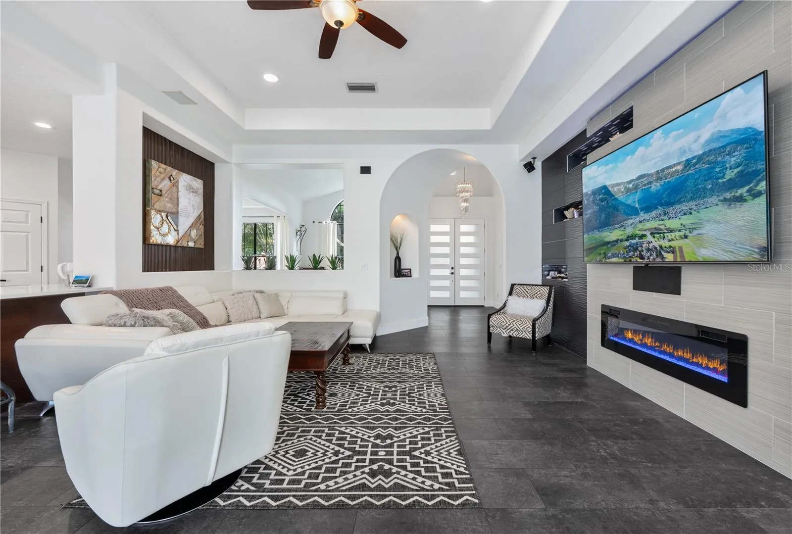Spacious family room featuring custom wall treatments, recessed display niches with LED lighting and decorative mosaic tile,  and a cozy fireplace.