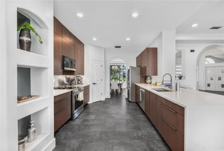 Modern kitchen featuring beautiful cabinetry, waterfall quartz counters, and stainless steel appliances.
