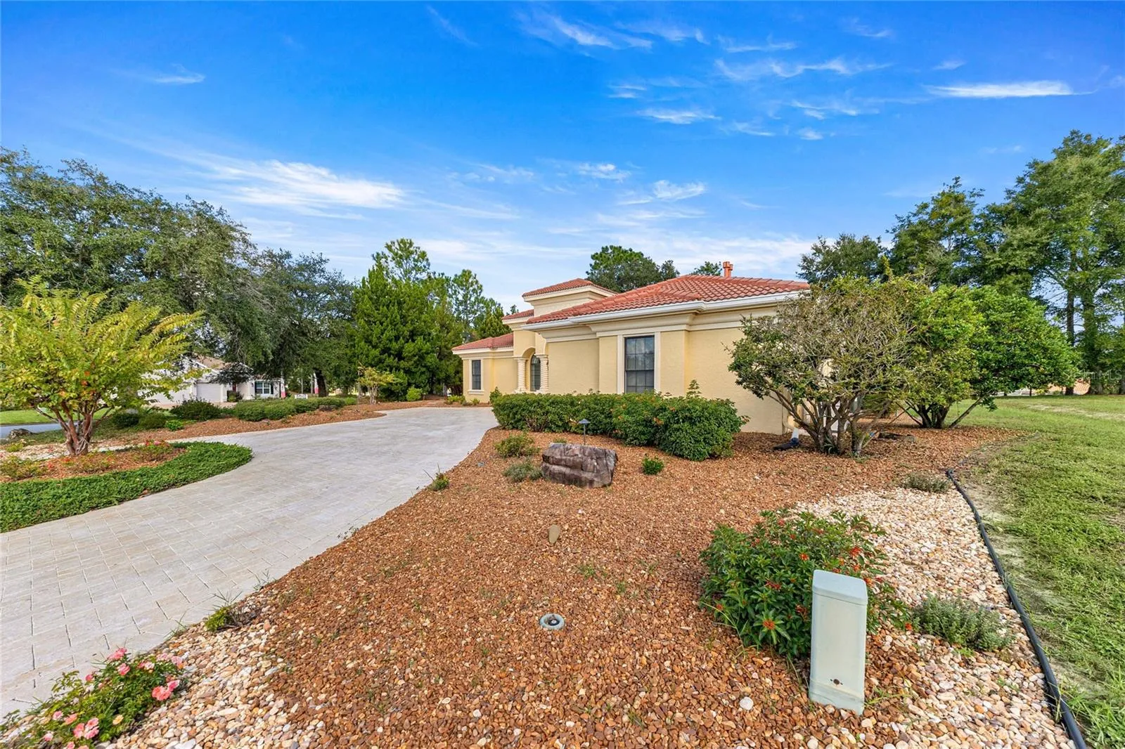 xterior View – Mediterranean-style home surrounded by mature landscaping and a spacious driveway.