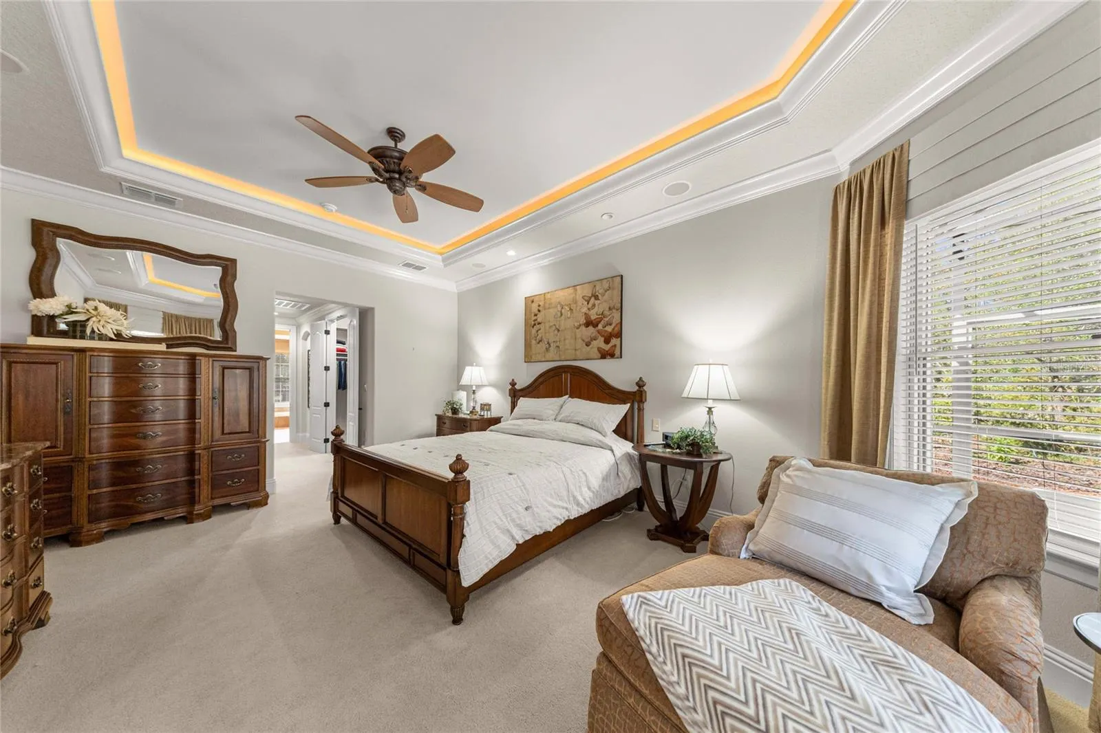 Beautiful owner's retreat offering generous space, a sitting area, and a distinctive illuminated tray ceiling.