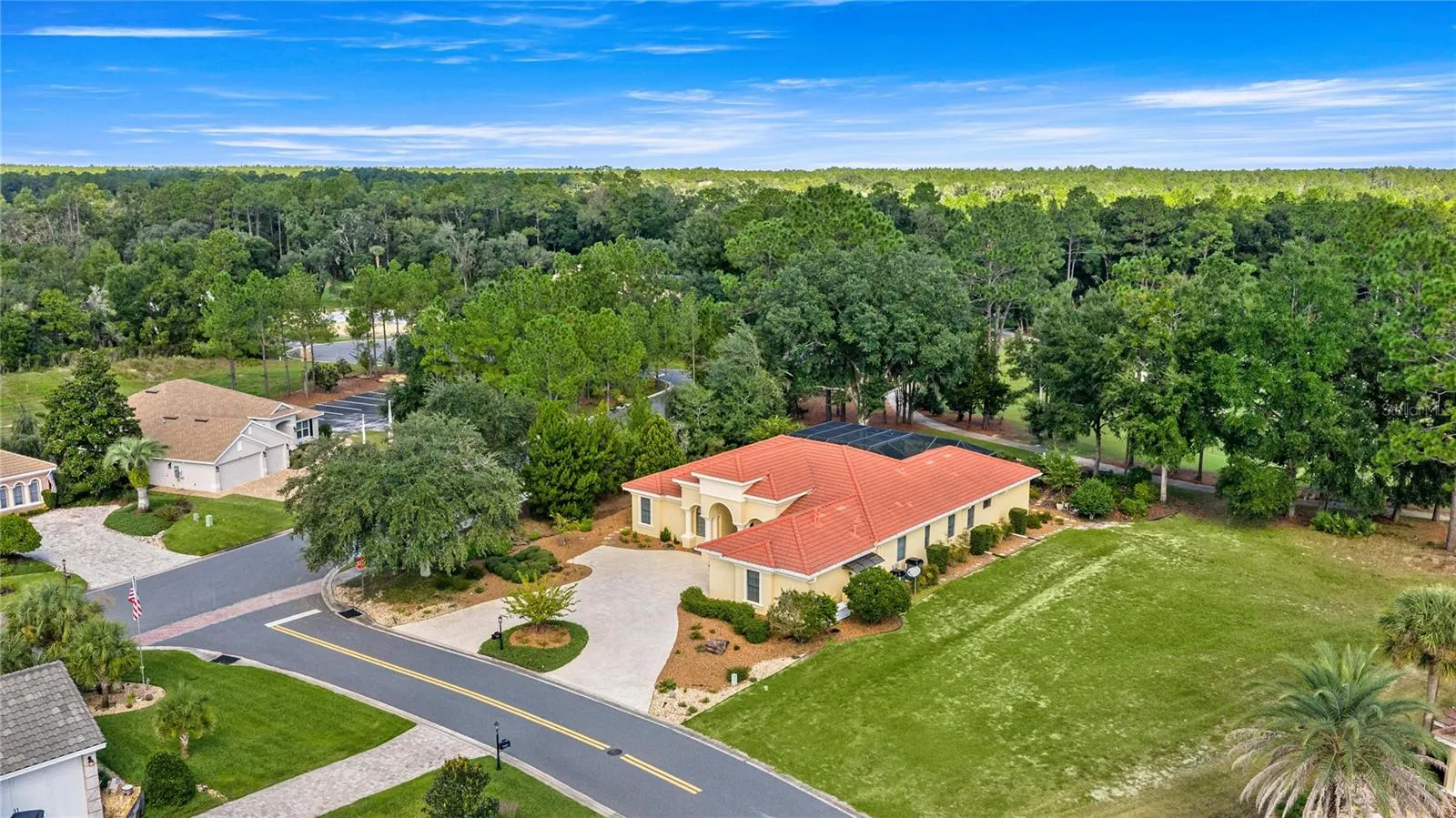 Spectacular aerial view showcasing the home's spacious setting, circular driveway, mature trees, and proximity to beautifully maintained golf course fairways.