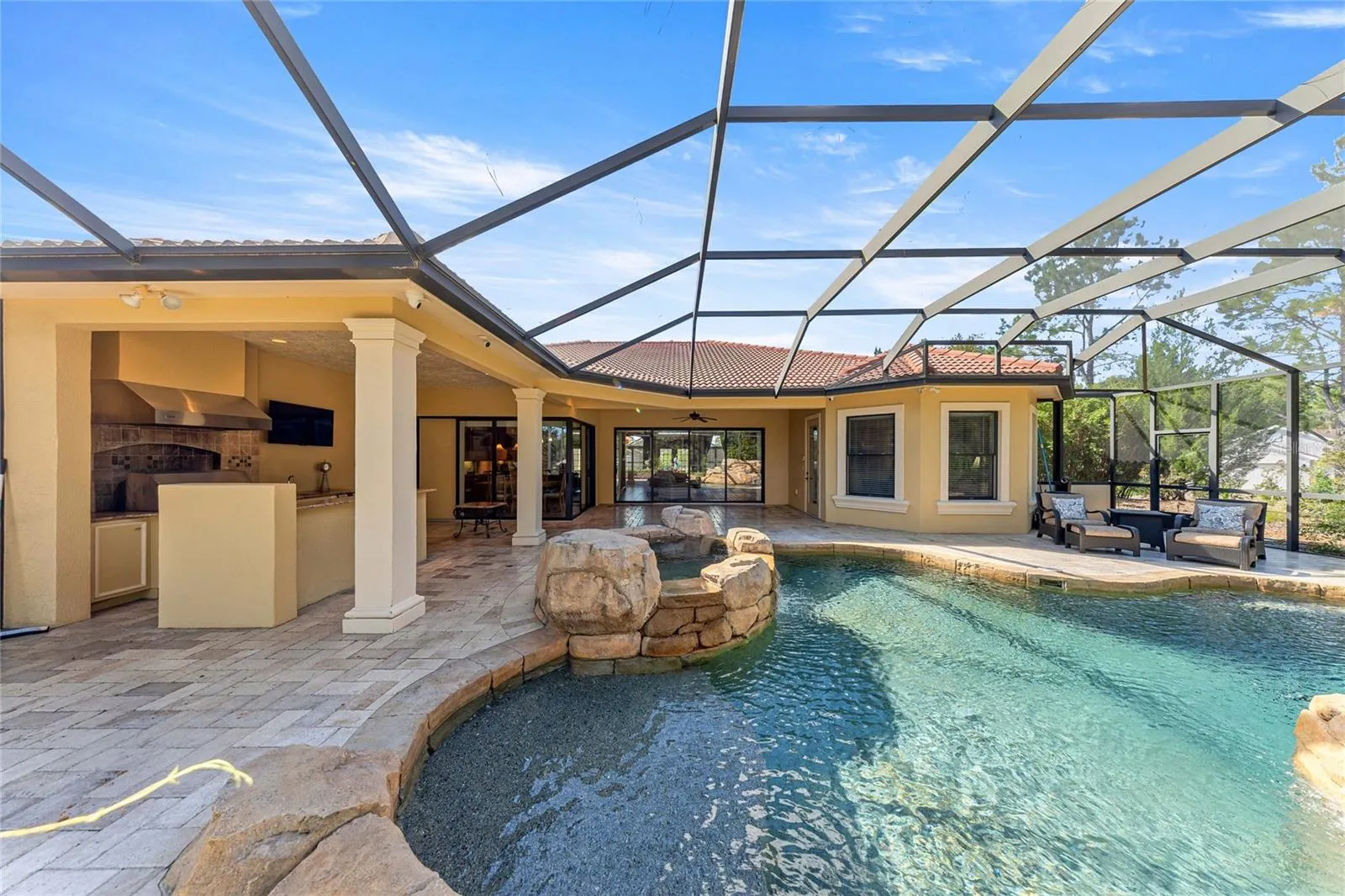 Screened Pool Area – Large screened enclosure with paver decking and views of the pool.