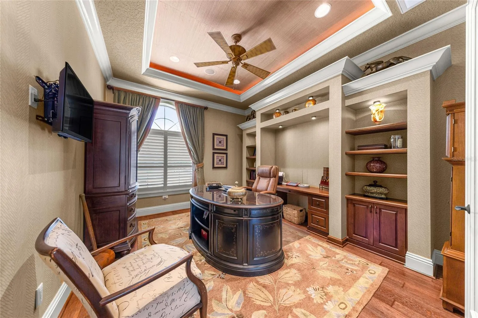 Elegant private office with double-door entry, custom shelving, built-in workspace, and decorative ceiling lighting.