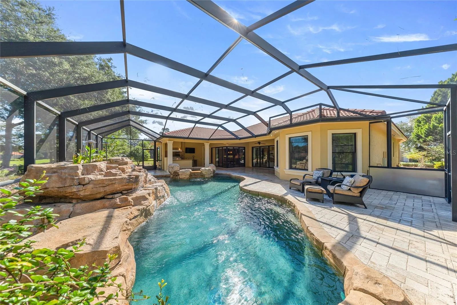 Screened Pool Enclosure – Expansive screened outdoor living area surrounded by natural landscaping.