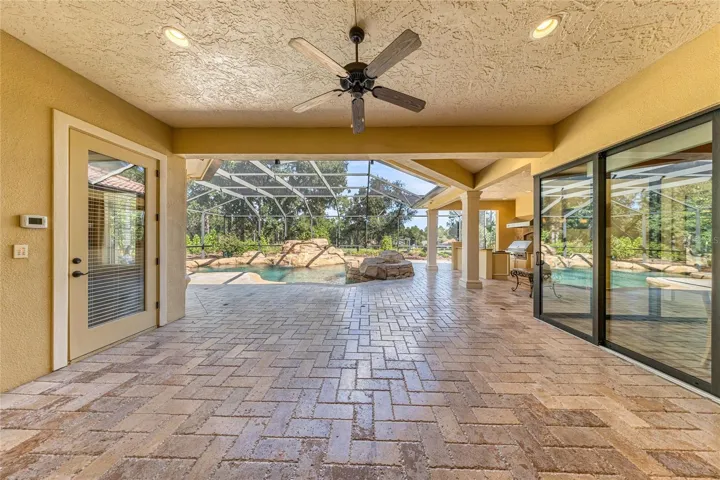 Oversized covered outdoor living area with fully opening sliding glass doors connecting to the main living space.