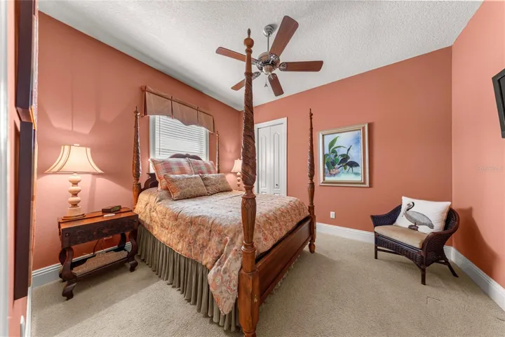 Inviting guest bedroom featuring warm designer colors, plush carpeting, ceiling fan.